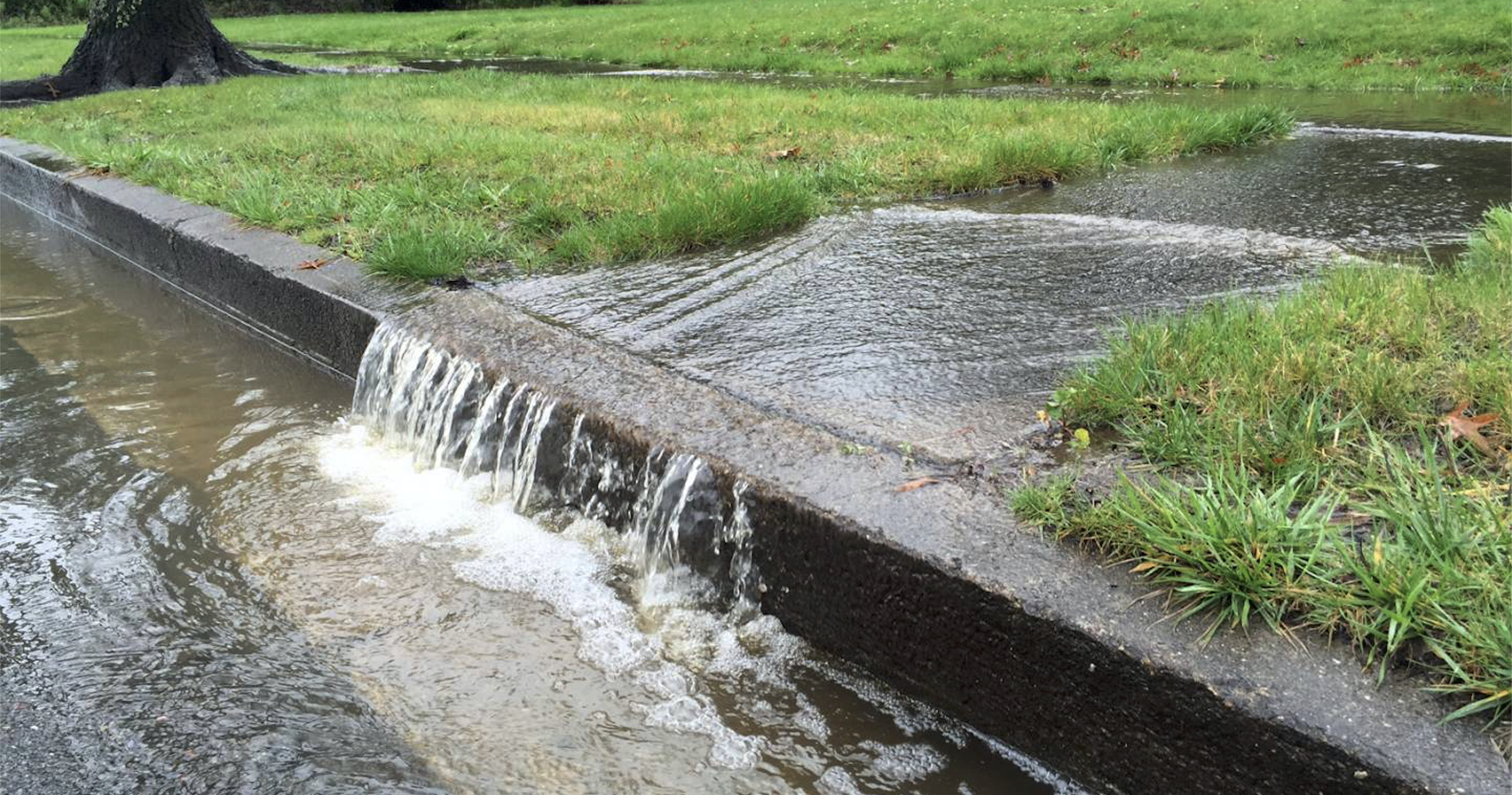 Stormwater runs off a sidewalk in a residential area