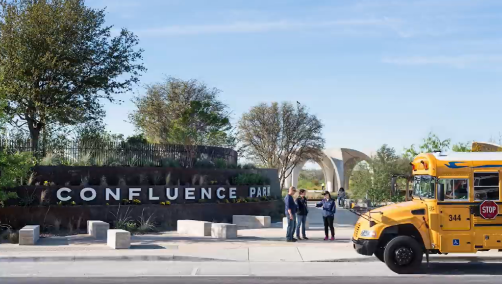 A school bus is parked in front of Confluence Park as students take part in a field trip.