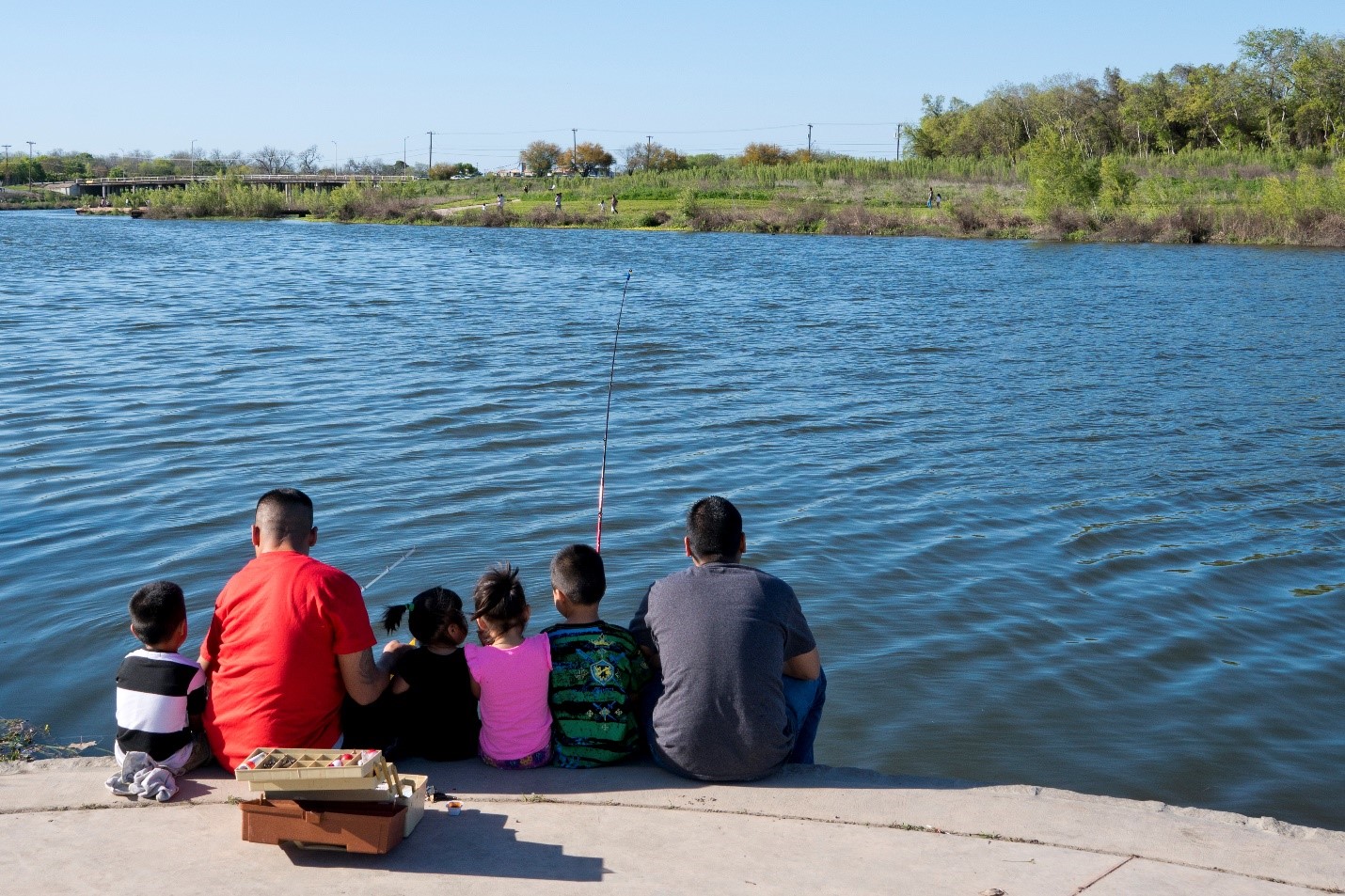 A family enjoys fishing on the Mission Reach of the San Antonio River Walk. 