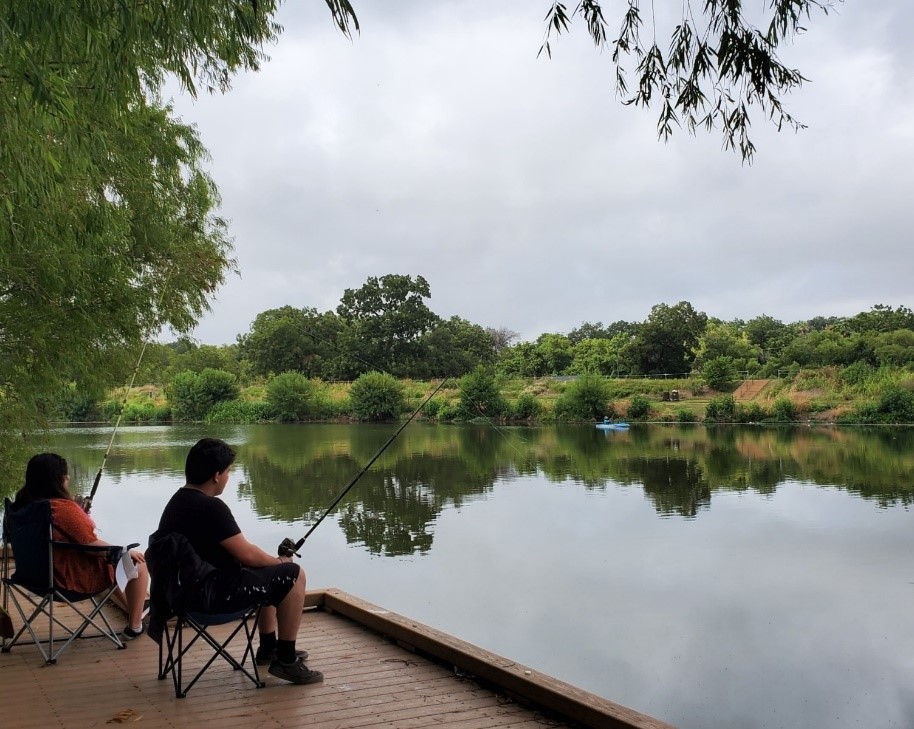 A family enjoying fishing on the Mission Reach segment of the San Antonio River Walk.