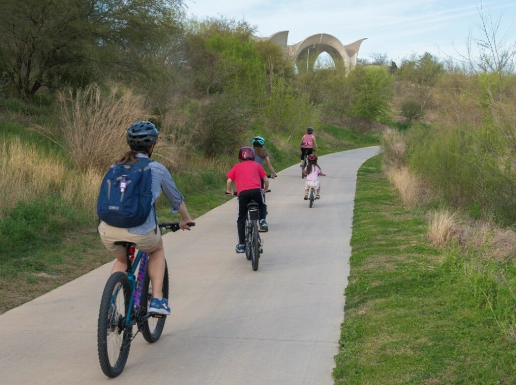A family bikes on the Mission Reach of the San Antonio River Walk.