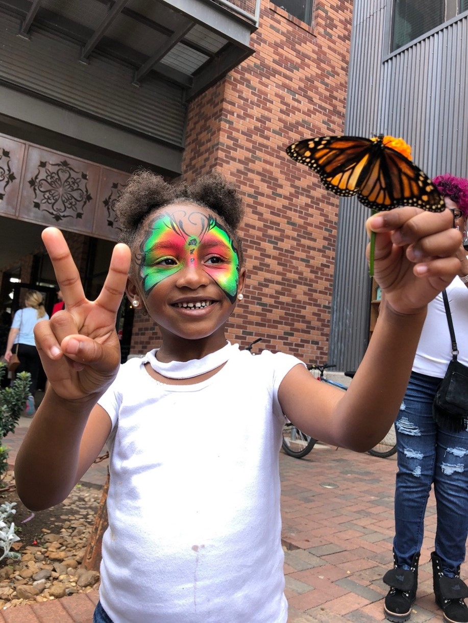 Participant holds monarch butterfly at the Monarch Butterfly and Pollinator Festival