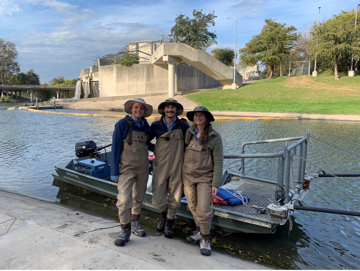 Three River Authority scientists pose in front of floating boat after fish survey has been completed.