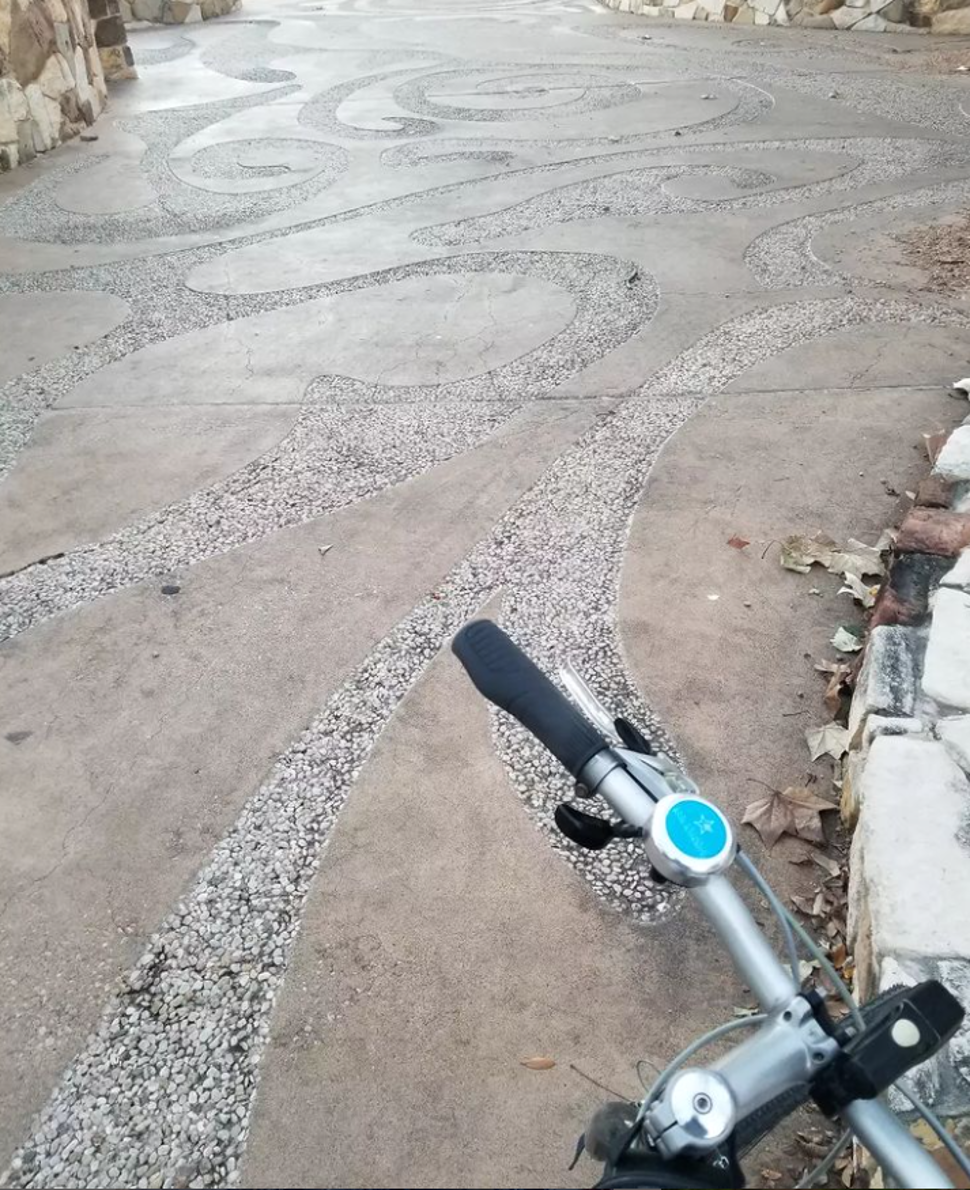 Angled view of bicycle handle with background showcasing wave patterns etched on the walking trails