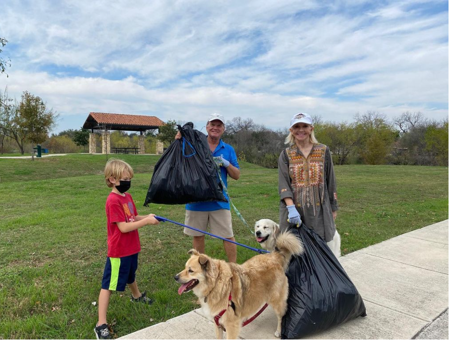 A family of tree with two large dogs pick up trash along Woodlawn Lake Park.
