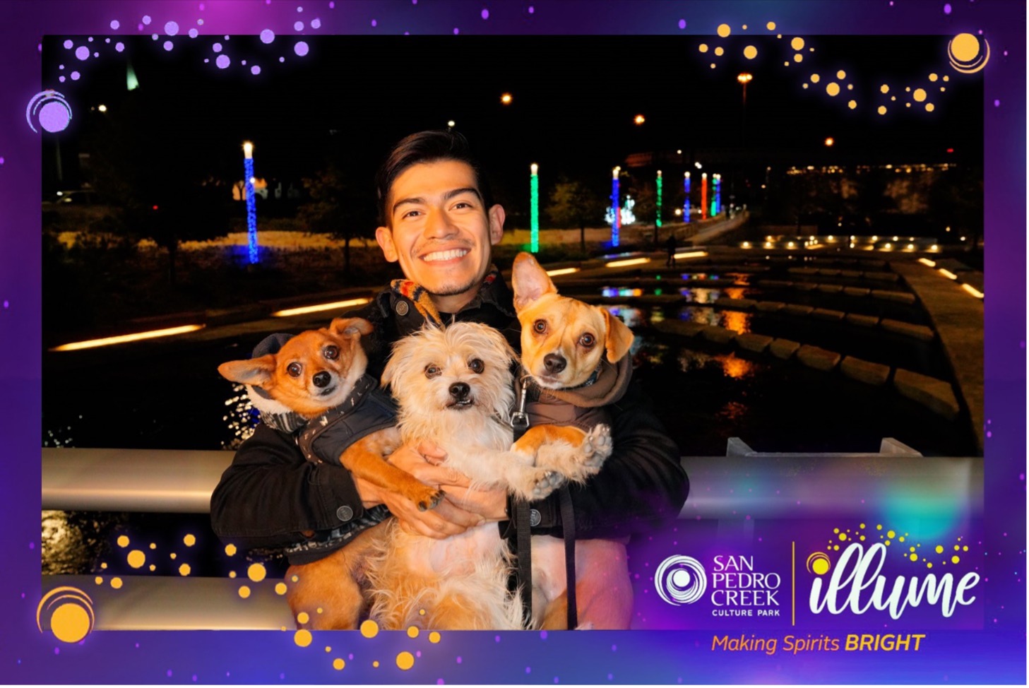 A young man poses with his three dogs in front on San Pedro Creek during Illume 2021