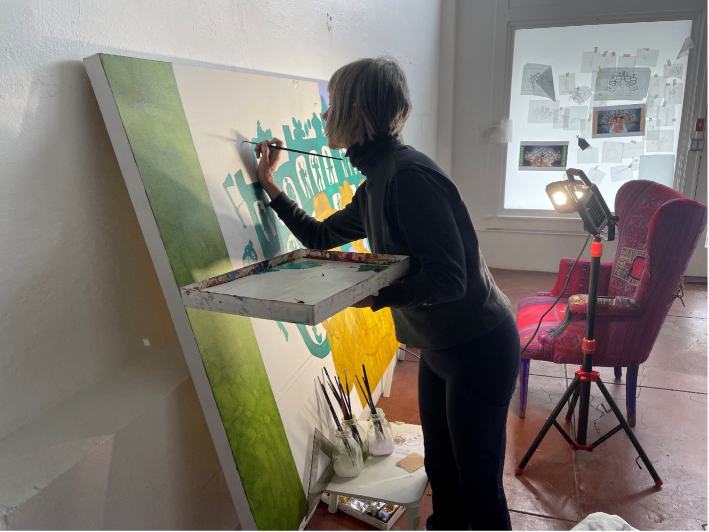 Artist Kathy Sosa paints the second panel of the 5 panel mural on large canvas in studio. 