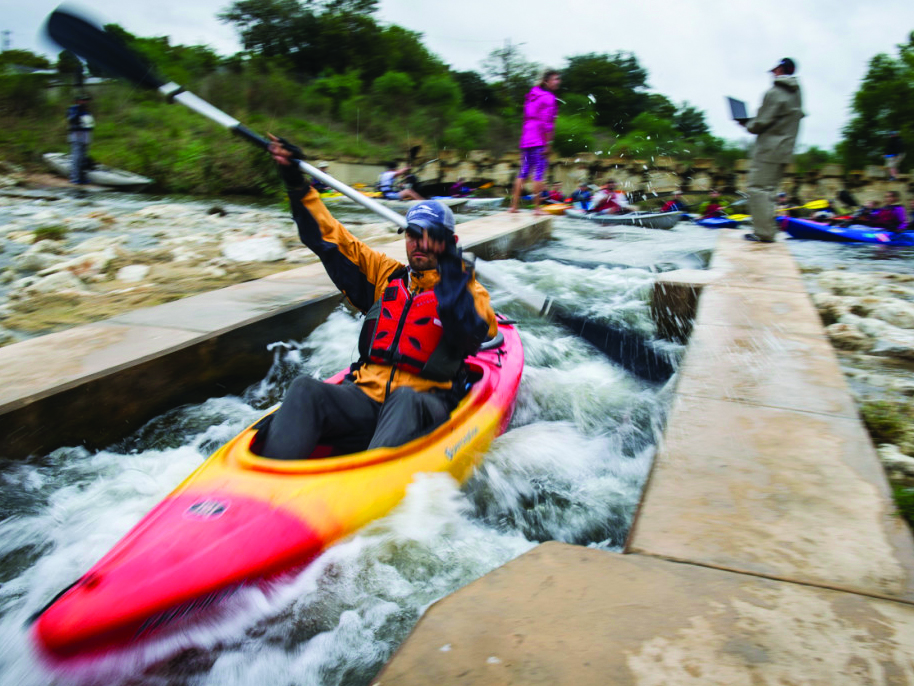A man races down the Mission Park waterway entry point in a kayak.