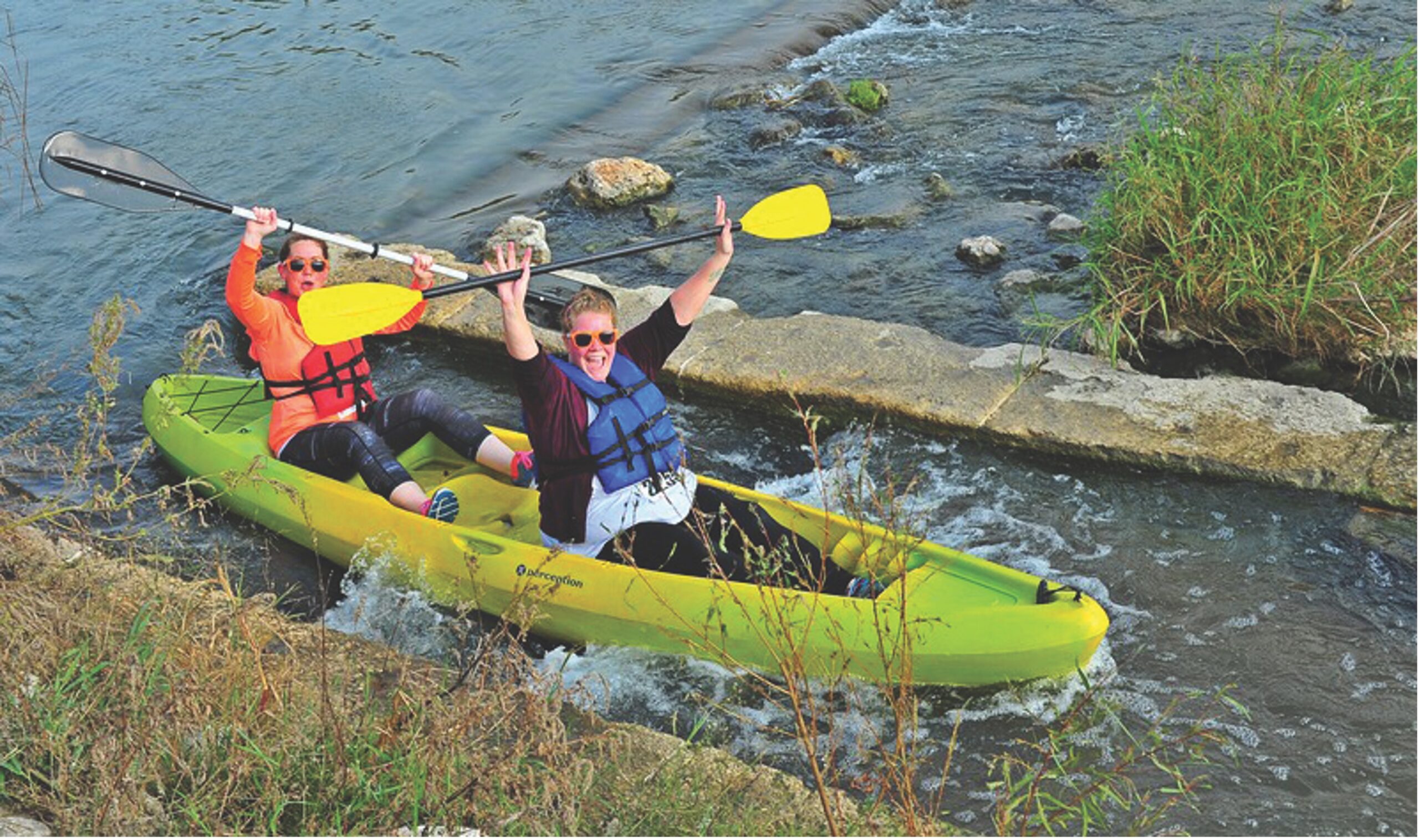 Two people in a tandem kayak show excitement floating down the San Antonio River. 