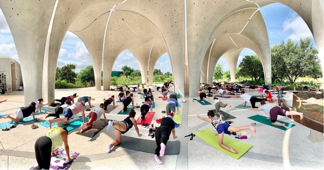 People stretch on yoga maps under the Confluence Park Pavilion Petals.