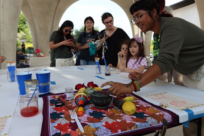 People gather round an art table to paint items at the Cochineala Art series event. 