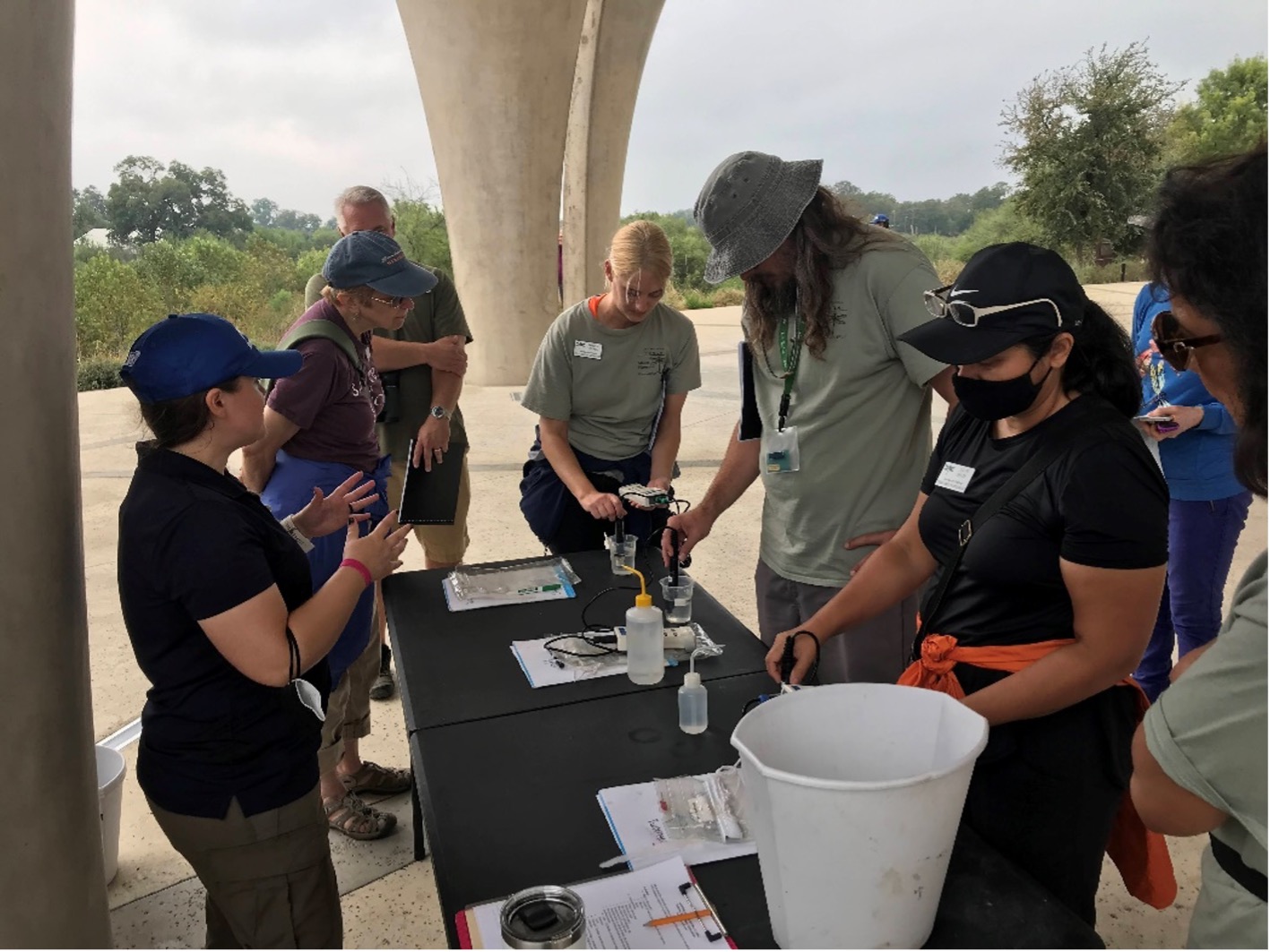 River Authority Education and Engagement Coordinator Janine Garcia teaches new AAMN volunteers about water quality in the river.