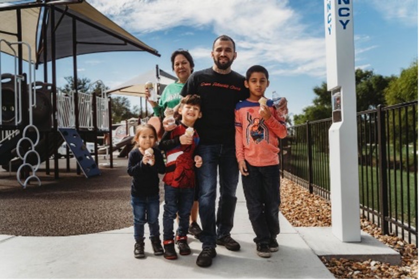 A family eats ice cream in front of the Escondido Creek Parkway playground.