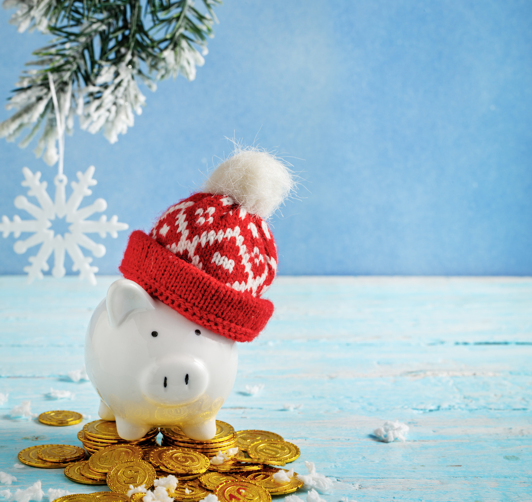 Piggybank with winter hat standing on top of gold coins