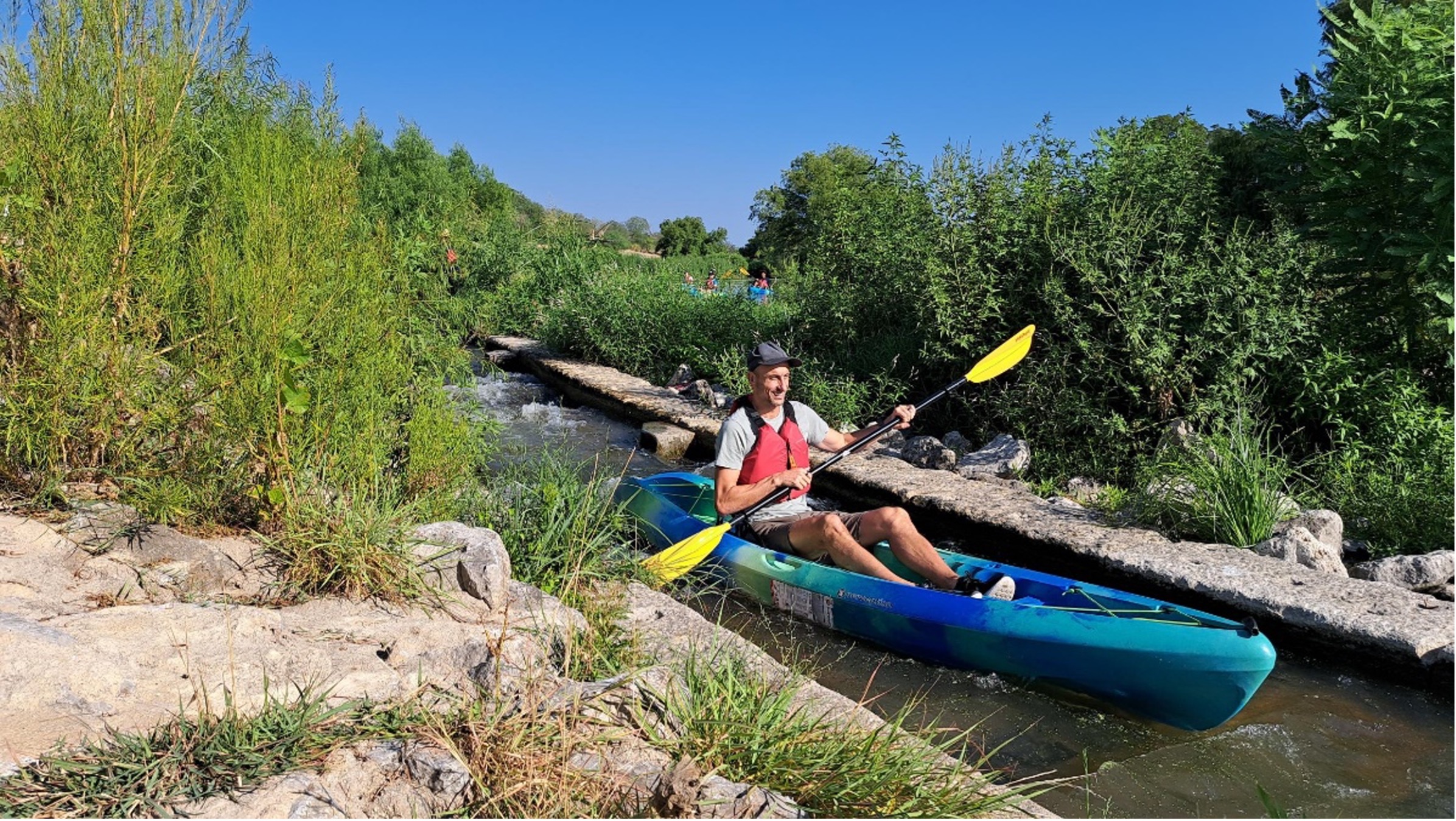 NBA Player Manu Ginobili in kayak paddling down the river