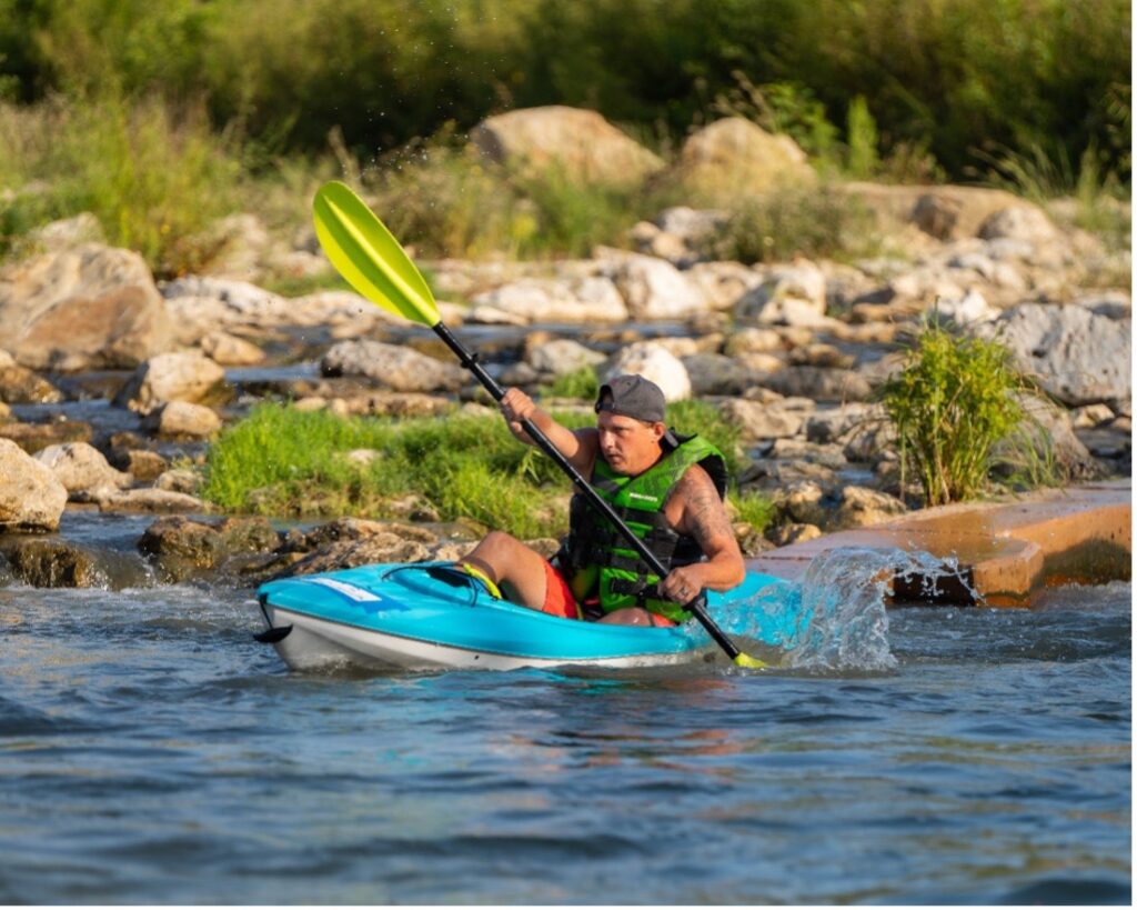 Paddler races through river during paddling race series.