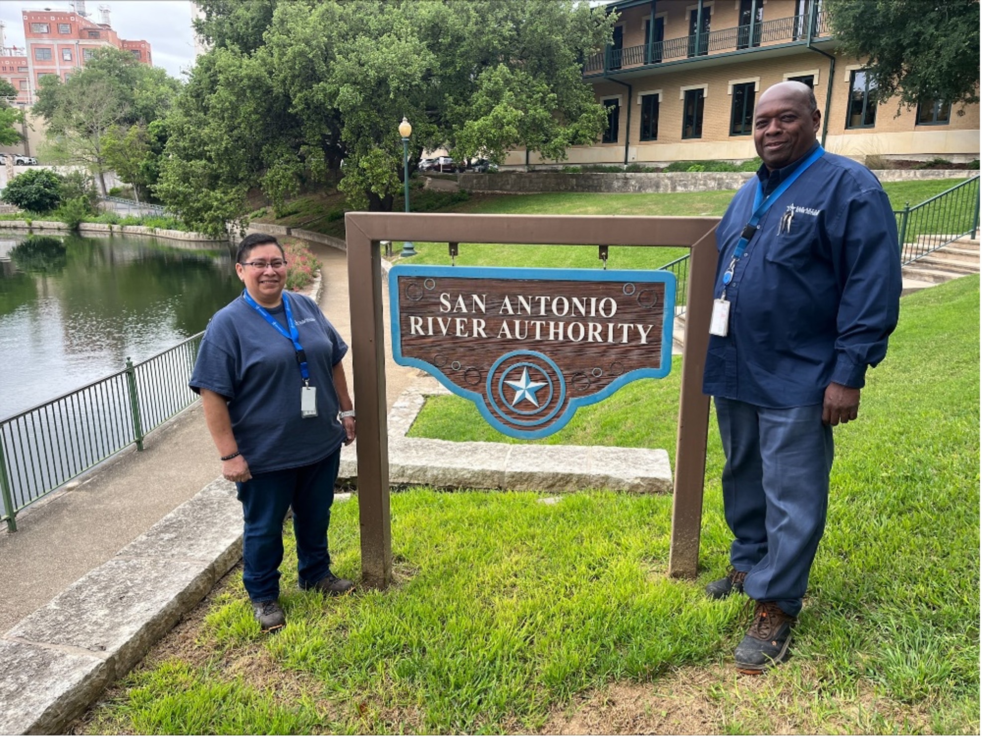 A man and woman pose next to San Antonio River Authority sign