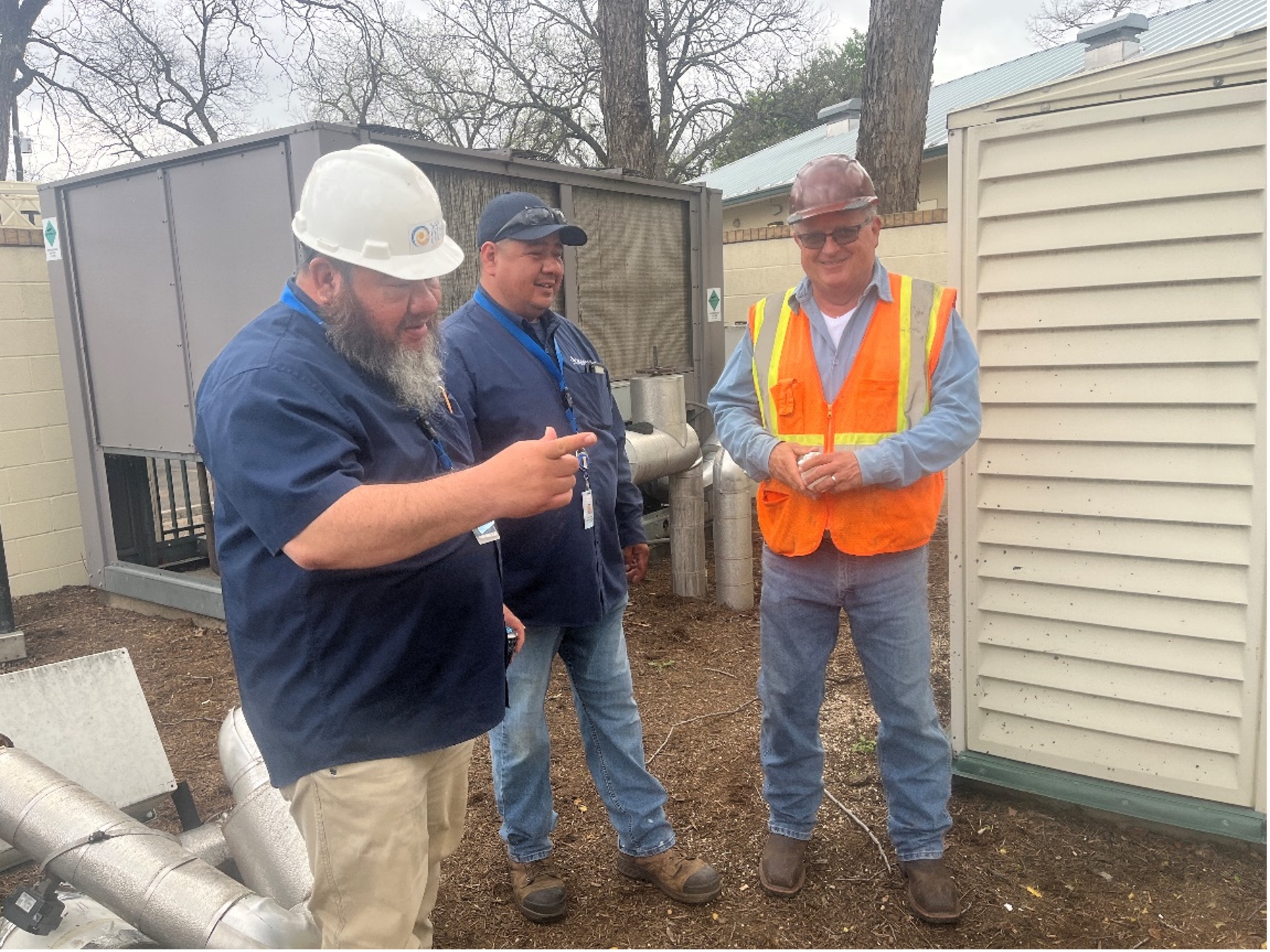 Three men in safety gear inspect new hvac chiller