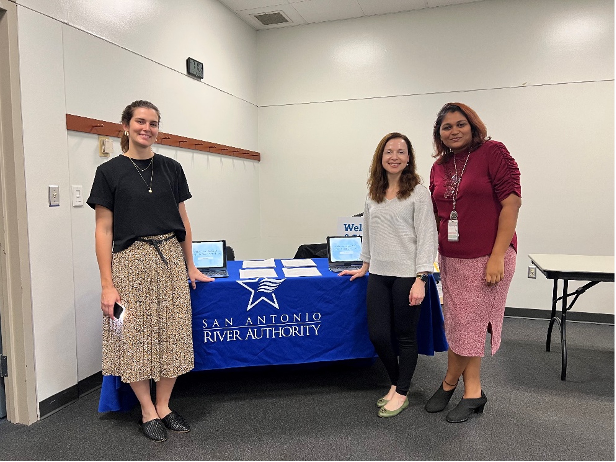 Three female ecological engineers standing near welcome table.