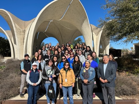 Teachers and leaders stand together in front of park pavilion.