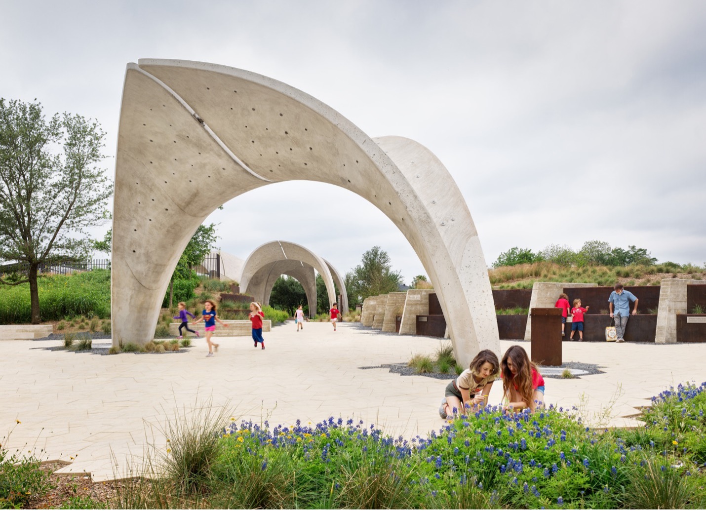 People walk through pavilion arches at Confluence Park