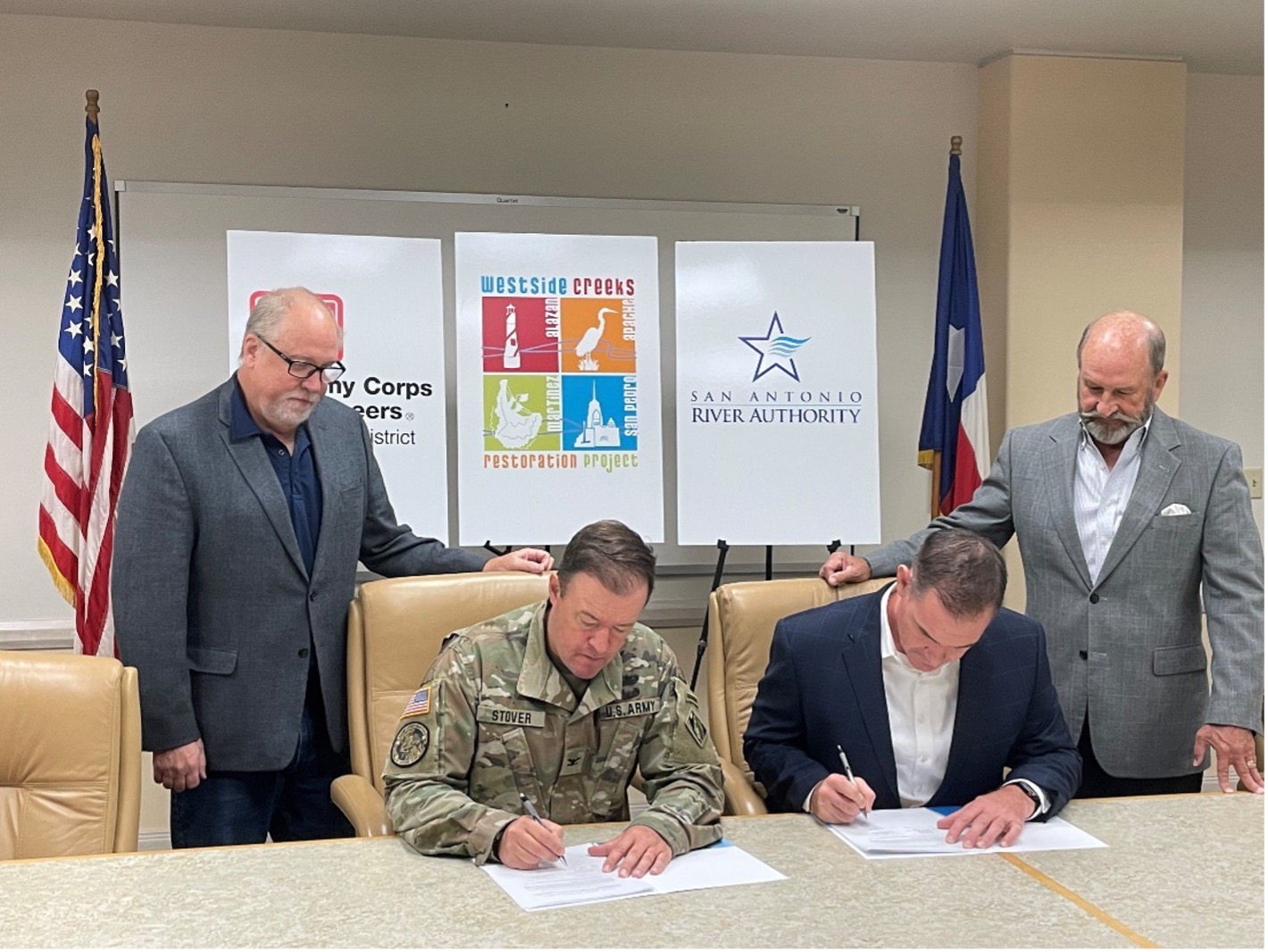 Four men gather together to sign papers.