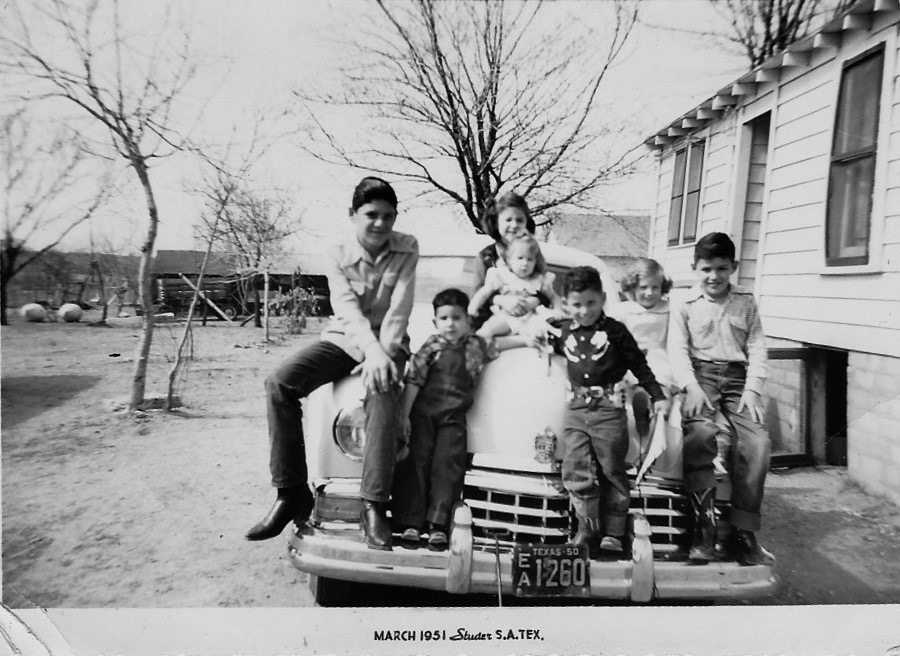 Children sit on hood of car.