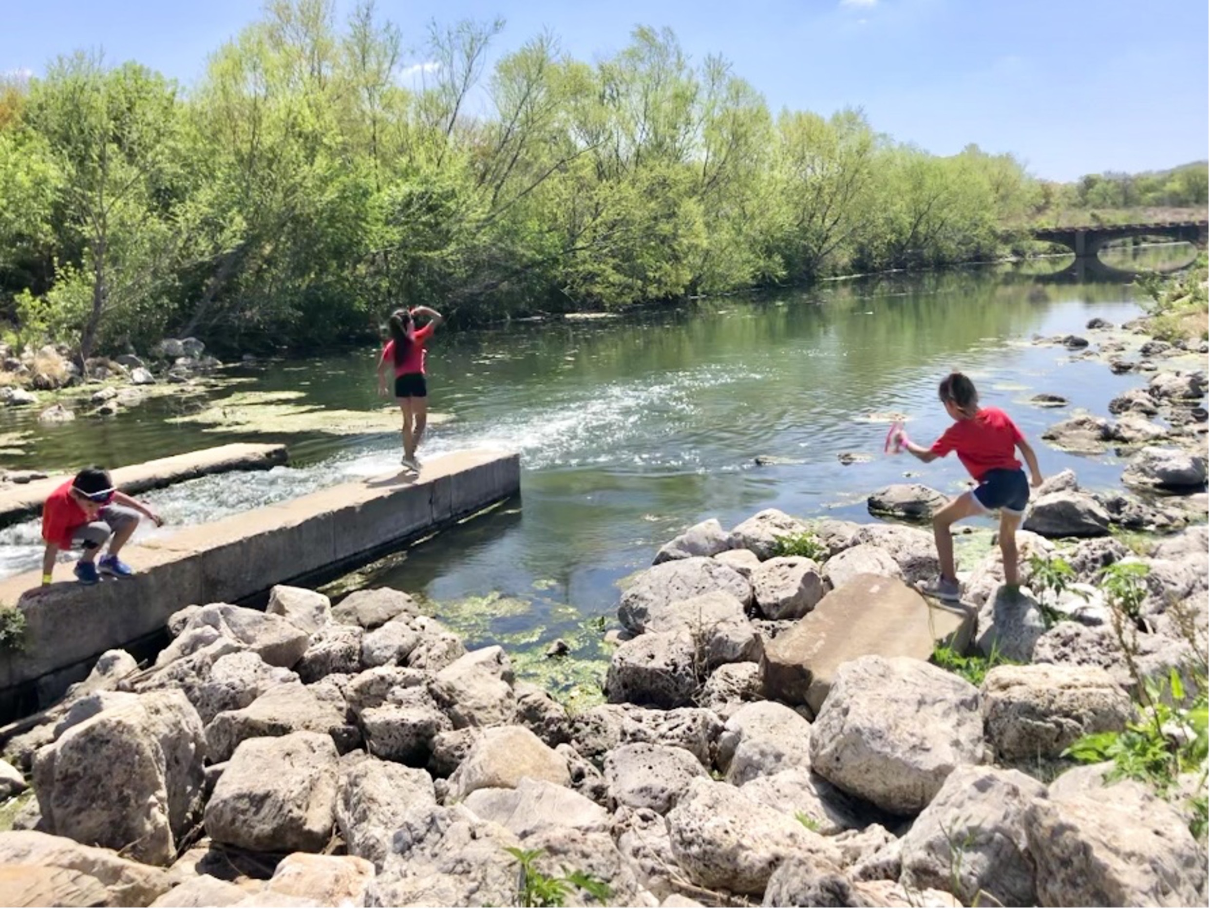 Three children play along the Mission Reach