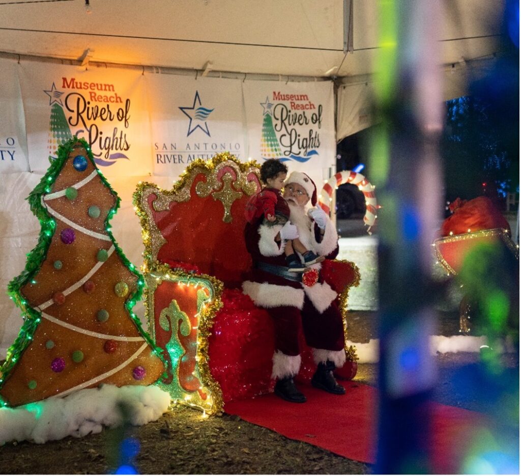 A child sits with Santa Claus during the River of Lights event