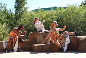 Three dancers pose on top of rocks.