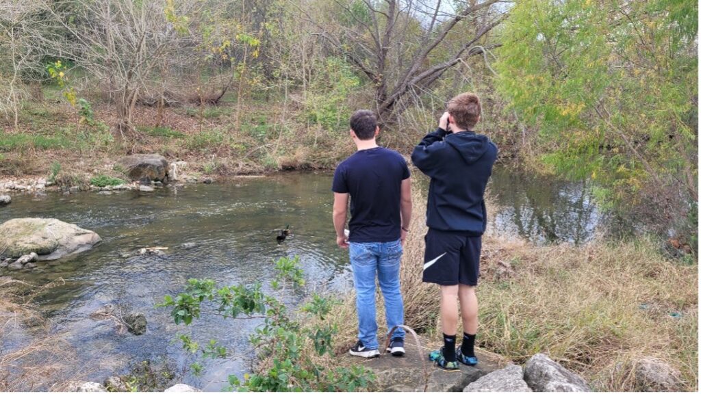 Two boys look out towards the river.