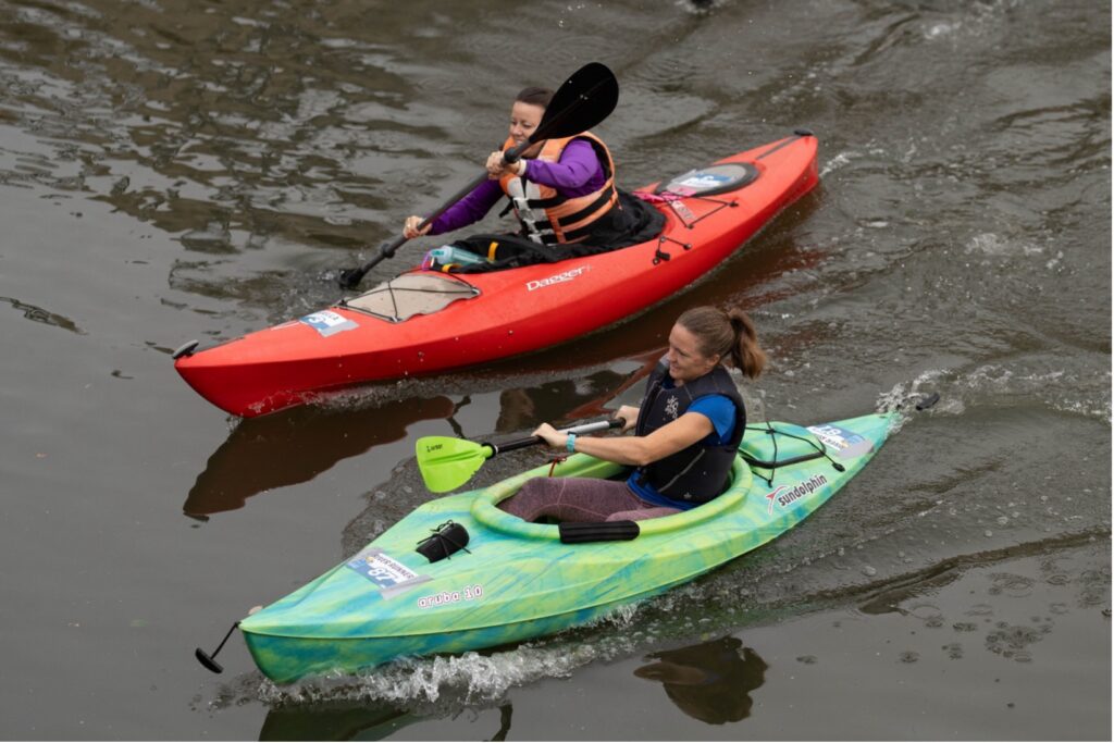 Two kayakers paddle down the river. 