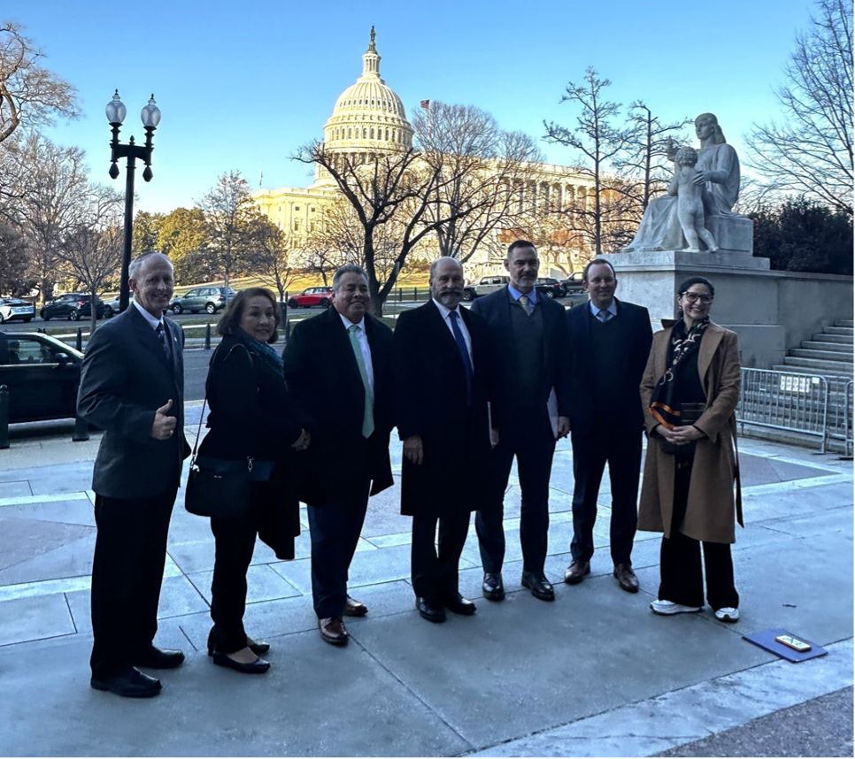 A group of people stands in front of the US Capital