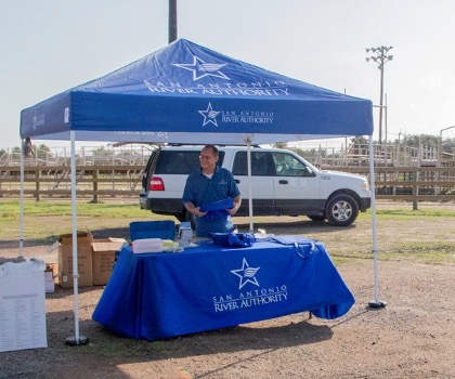 A man stands under a tent behind a table.