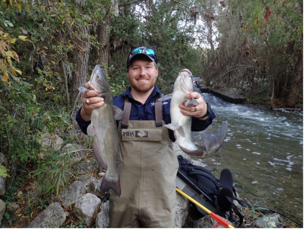 An Aquatic Biologist holds up two fish