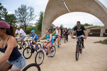 A group of cyclists ride by Confluence Park