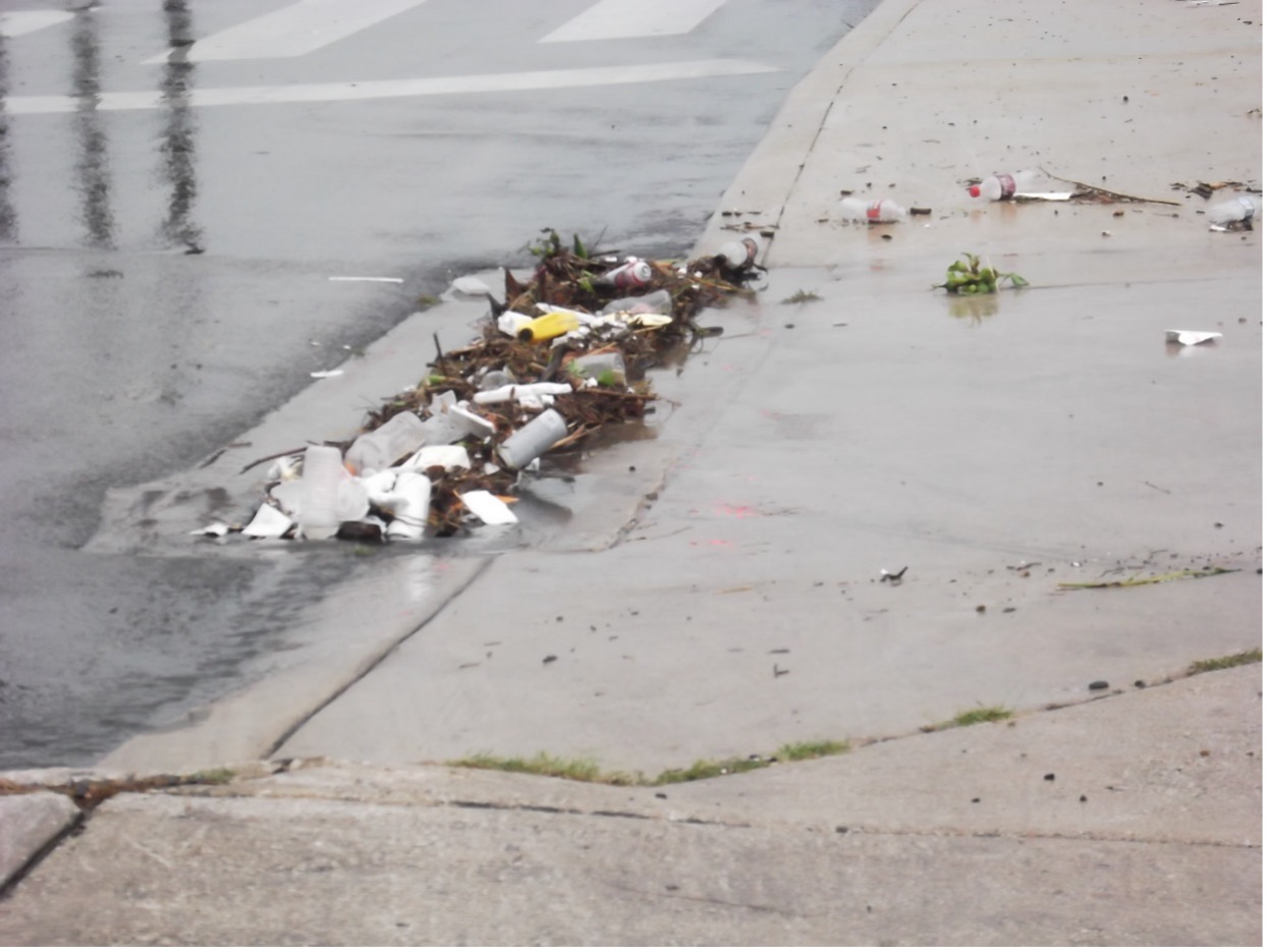 Styrofoam cups and other litter crowd the drainage in city roads after heavy rain event