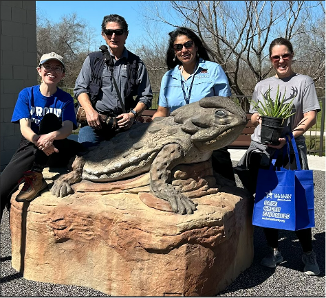 Team members pose near the horned toad statue 