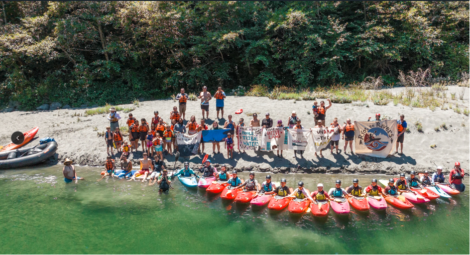 People sitting on island beach with kayaks and paddles