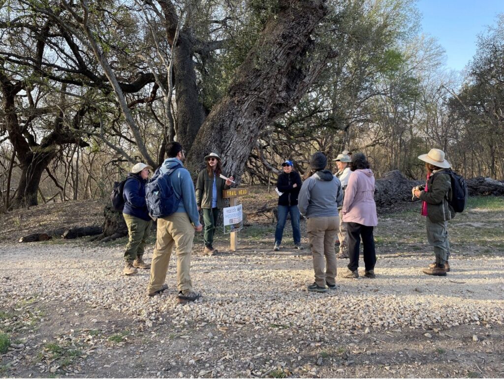 A group of people create a circle to get ready for a nature hike.