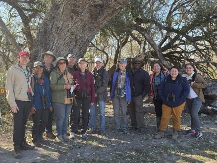 A group of people gather around to take a photo together.