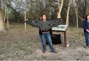 A woman holds up a cloth with different bat wing widths on it