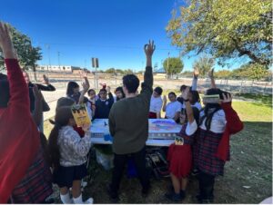 Students gather around educational table setup.