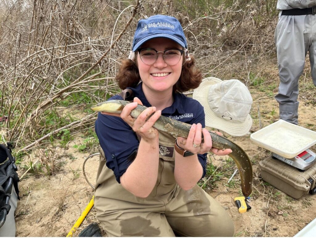 Caille Marshall an Environmental Scientist holding an adult American Eel
