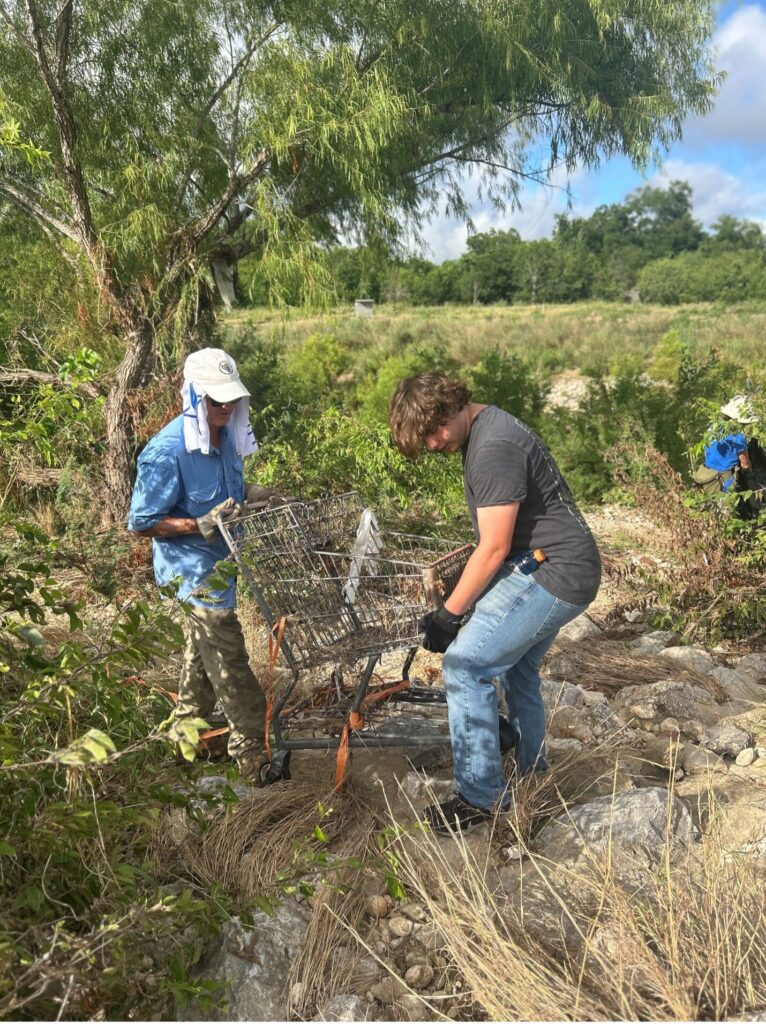 Volunteers remove grocery basket from a field. 