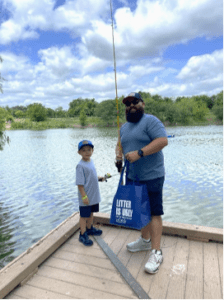 A father and son stand next to a fishing dock.