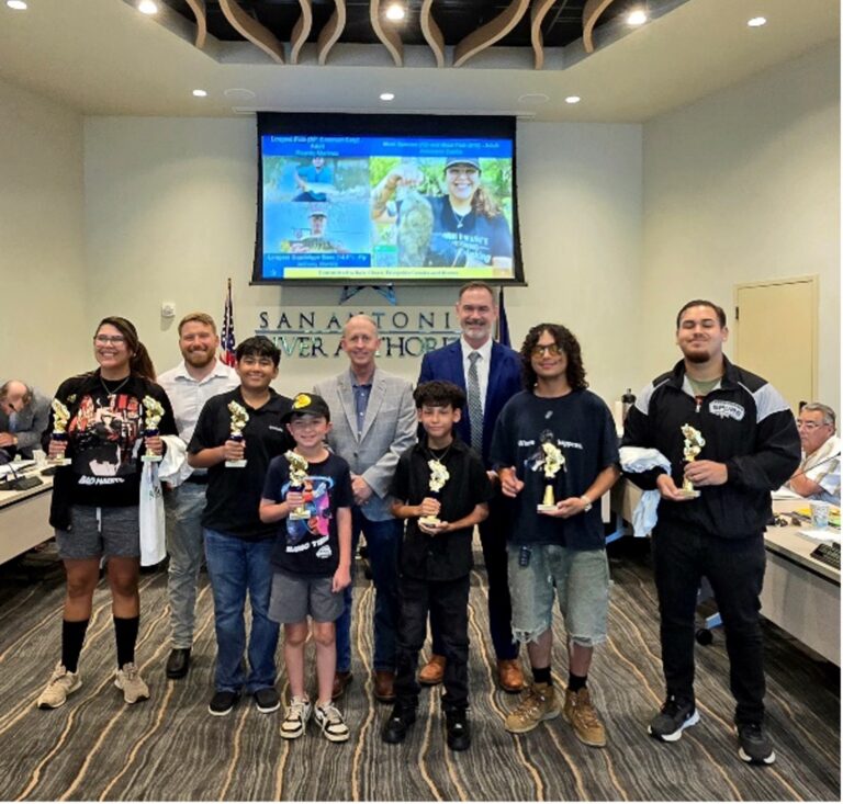 A group of students accept their trophis for winning the River Rodeo Fishing Tournament Challenge