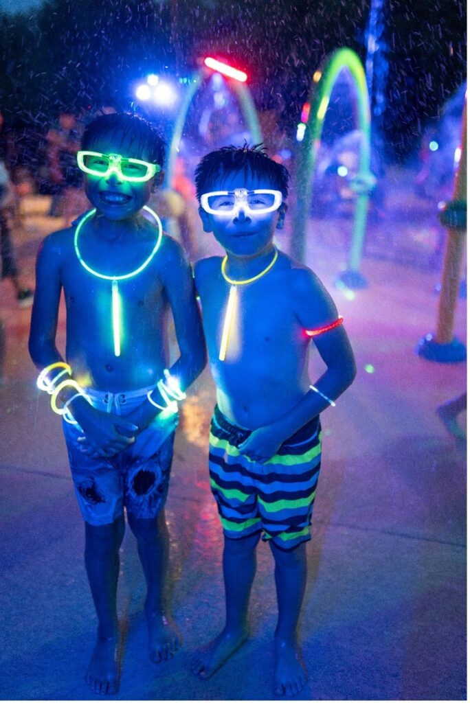 Two boys with glow sticks at a splashpad