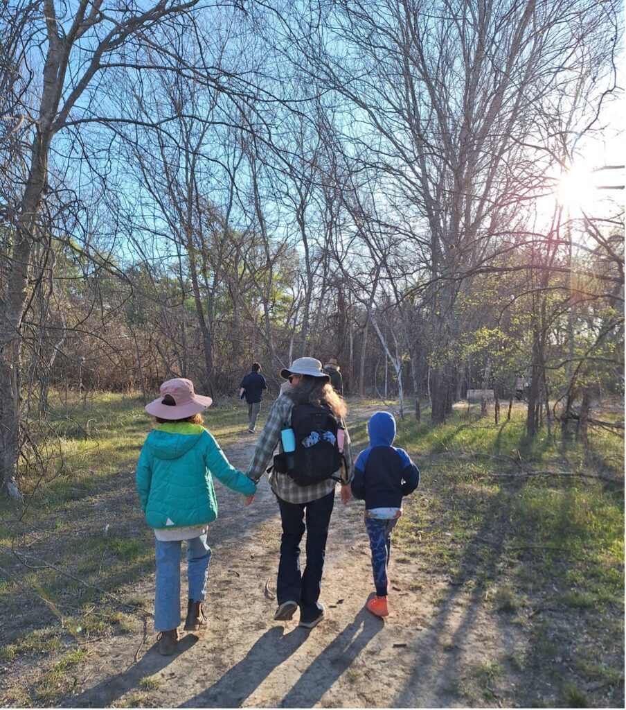 A Mother and her two children walk on park trail together