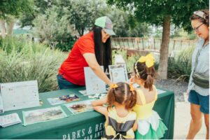 Pollinator festival booth with woman and two children interacting